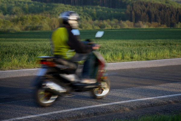 Tonåring som kör moped ute på landsväg.